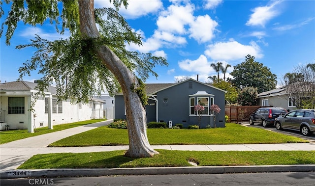 view of front of house featuring stucco siding, fence, and a front yard