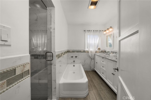 full bathroom with vanity, tile walls, wainscoting, a garden tub, and a stall shower
