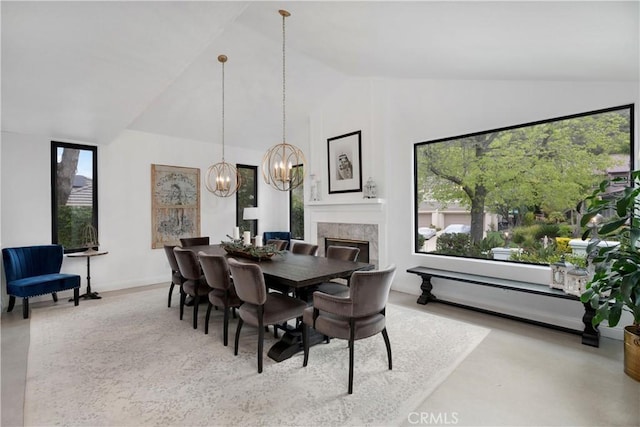 dining space featuring baseboards, high vaulted ceiling, an inviting chandelier, and a high end fireplace