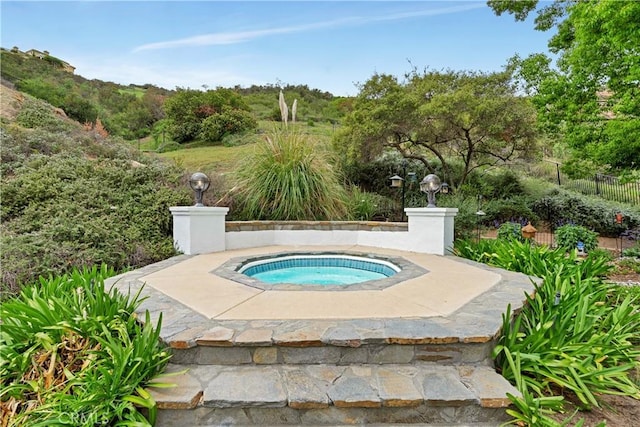 view of swimming pool with fence and an in ground hot tub