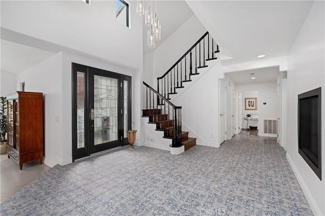 foyer with carpet flooring, an inviting chandelier, stairs, visible vents, and baseboards