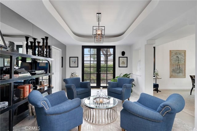 living area with baseboards, french doors, and a tray ceiling