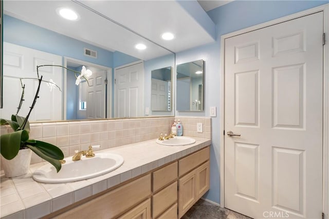 bathroom with double vanity, visible vents, backsplash, and a sink