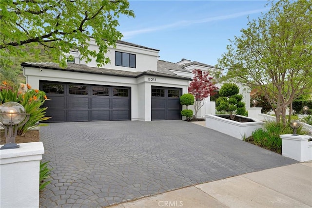 view of front of home with stucco siding, decorative driveway, and an attached garage