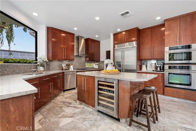 kitchen featuring a sink, visible vents, stainless steel appliances, wall chimney exhaust hood, and wine cooler