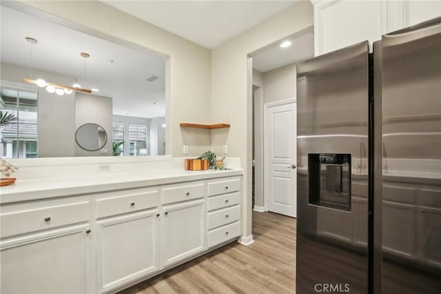 kitchen featuring white cabinets, visible vents, light wood-style floors, stainless steel fridge with ice dispenser, and light countertops