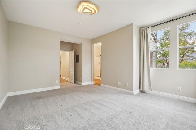 empty room featuring baseboards and light carpet