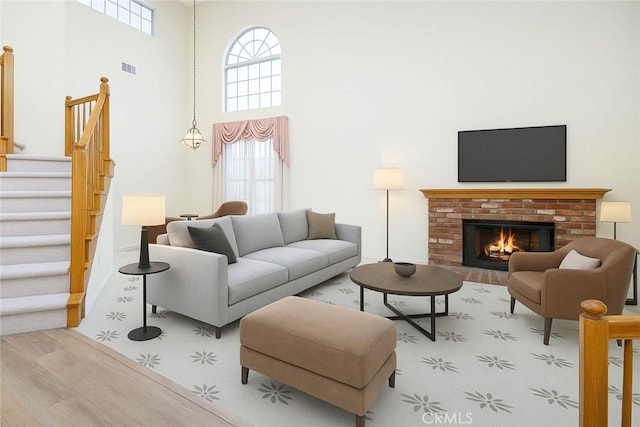 6721 Silver Oak Pl, Riverside, CA 92506 - living room featuring a high ceiling, wood finished floors, visible vents, a fireplace, and stairs