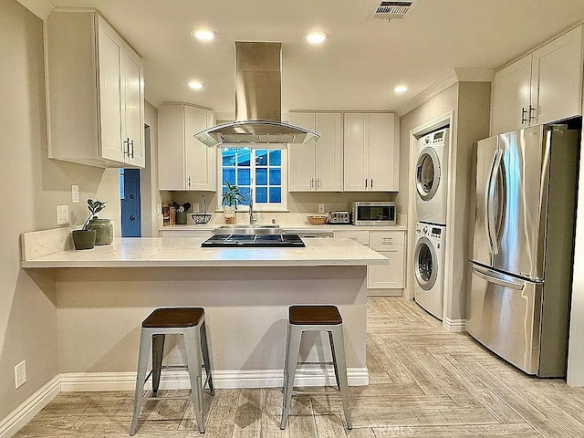 642 W Wilson St, Costa Mesa, CA 92627 - kitchen with appliances with stainless steel finishes, island exhaust hood, stacked washer / drying machine, a peninsula, and ornamental molding