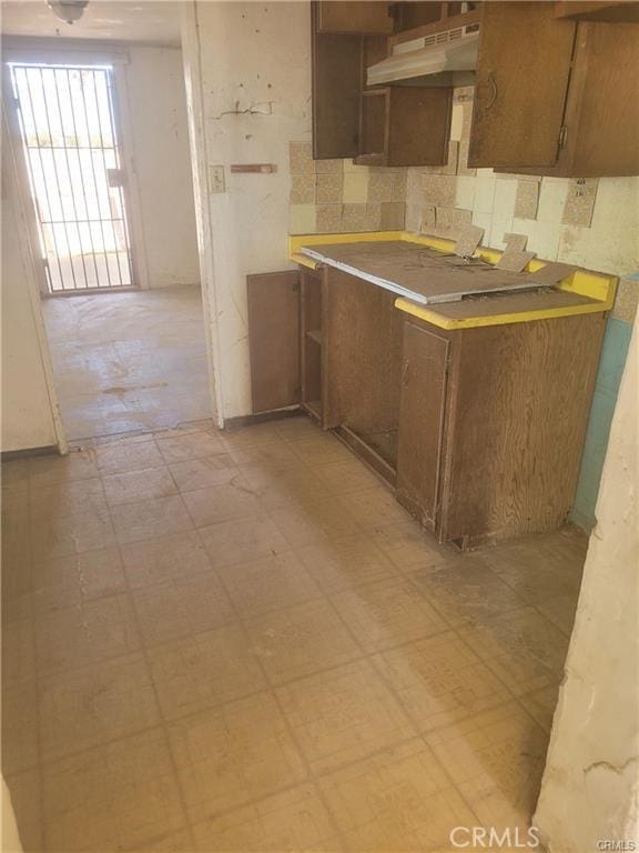 21284 Santa Fe Ave, Hinkley, CA 92347 - kitchen with decorative backsplash, brown cabinets, light floors, light countertops, and under cabinet range hood