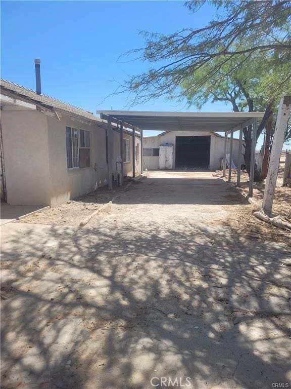 21284 Santa Fe Ave, Hinkley, CA 92347 - view of side of home featuring stucco siding, an outdoor structure, and a carport