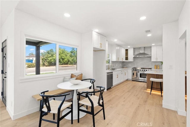 786 Carhart Ave, Fullerton, CA 92833 - kitchen featuring wall chimney range hood, appliances with stainless steel finishes, light countertops, white cabinetry, and decorative backsplash