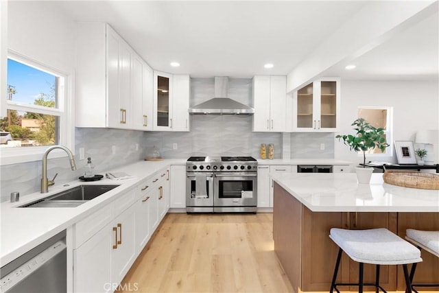 786 Carhart Ave, Fullerton, CA 92833 - kitchen with wall chimney range hood, stainless steel appliances, light countertops, a kitchen bar, and light wood-type flooring
