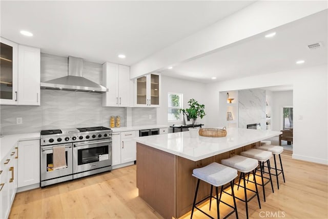 786 Carhart Ave, Fullerton, CA 92833 - kitchen with wall chimney exhaust hood, double oven range, light wood-style flooring, a breakfast bar area, and a kitchen island