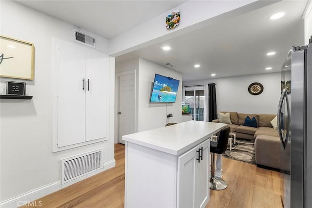 28691 Via Las Flores Unit 328, Murrieta, CA 92563 - kitchen with freestanding refrigerator, open floor plan, light wood finished floors, white cabinets, and recessed lighting