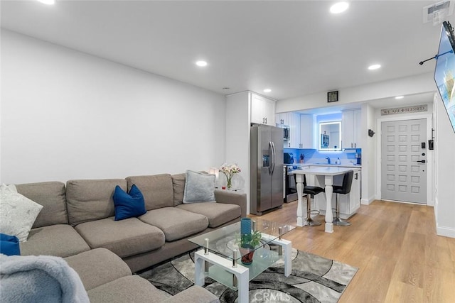 living area featuring baseboards, light wood-style flooring, visible vents, and recessed lighting