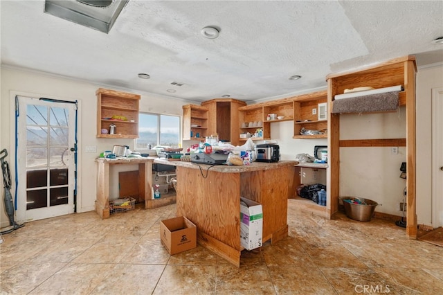 kitchen featuring a center island, open shelves, a textured ceiling, a breakfast bar, and light countertops