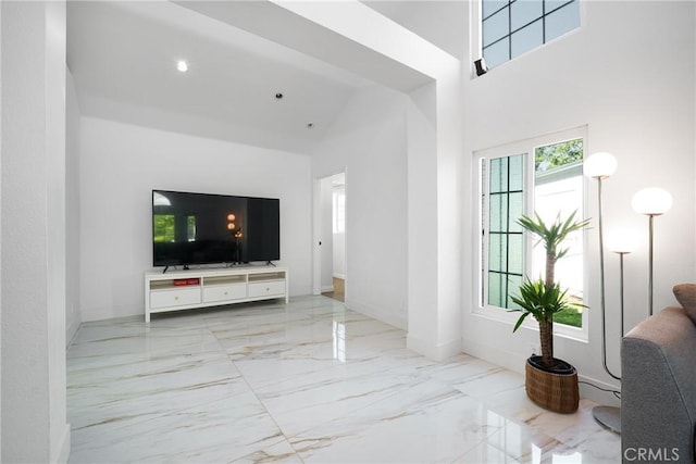 living room with baseboards, a high ceiling, and marble finish floor