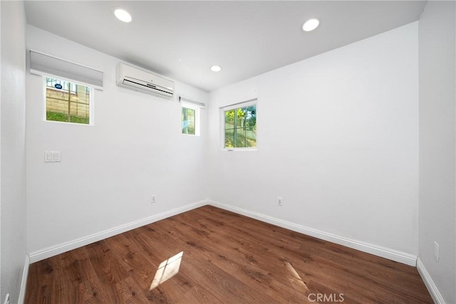spare room with wood finished floors, baseboards, recessed lighting, and a wall mounted air conditioner