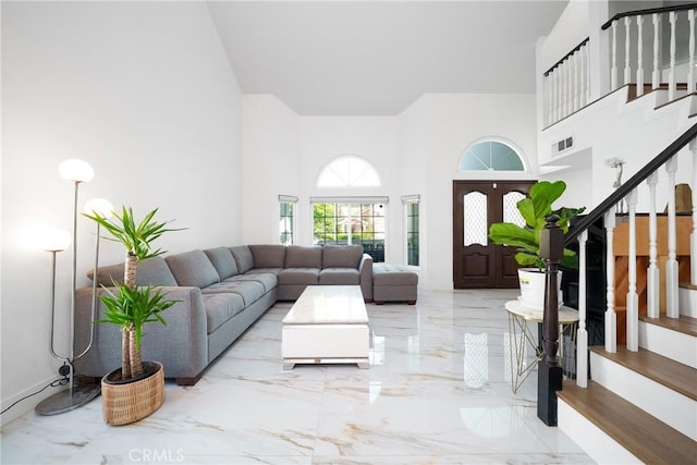living room with marble finish floor, a high ceiling, stairs, and visible vents