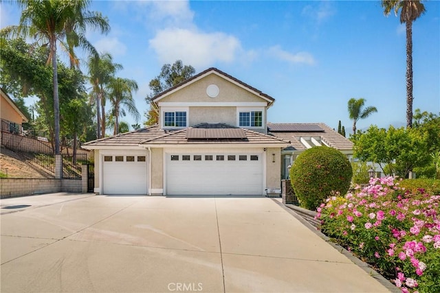 traditional-style home with roof mounted solar panels, a tiled roof, driveway, and stucco siding