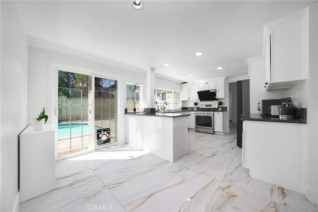 kitchen featuring white cabinets, dark countertops, gas range, and recessed lighting