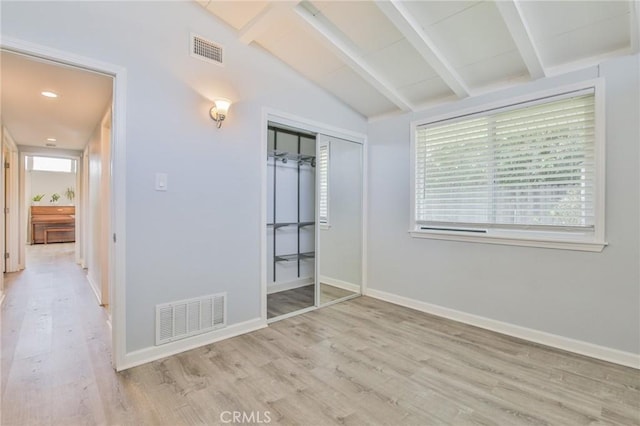 unfurnished bedroom with wood finished floors, vaulted ceiling with beams, visible vents, and multiple windows