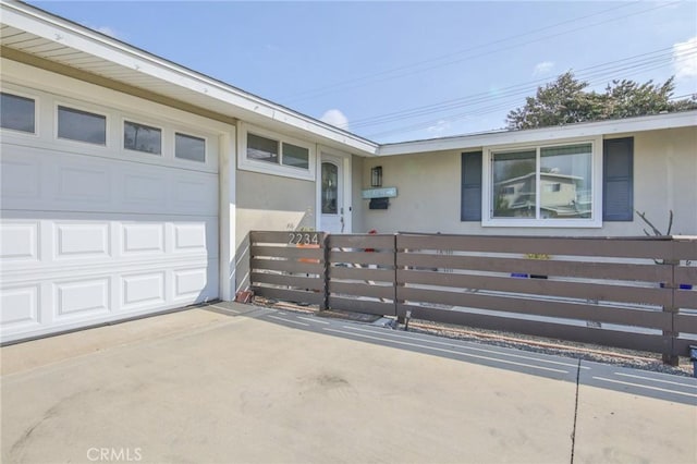 view of front of property with stucco siding, fence, concrete driveway, and a garage