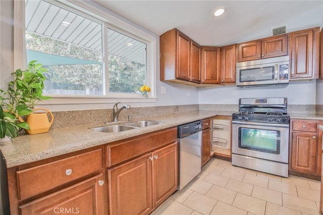 kitchen with stainless steel appliances, a sink, visible vents, brown cabinetry, and light tile patterned floors