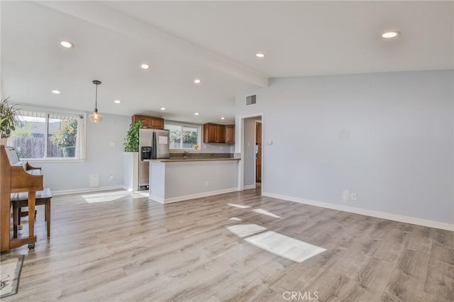 unfurnished living room featuring recessed lighting, light wood finished floors, baseboards, and vaulted ceiling with beams
