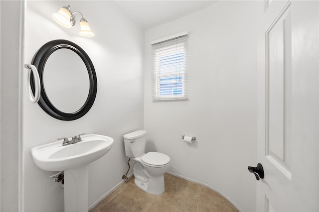 half bath with toilet, baseboards, and tile patterned flooring