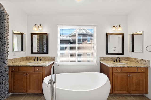 full bath featuring a sink, a freestanding bath, and tile patterned floors