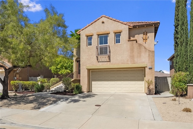 mediterranean / spanish house featuring stucco siding, a tiled roof, an attached garage, driveway, and stairway