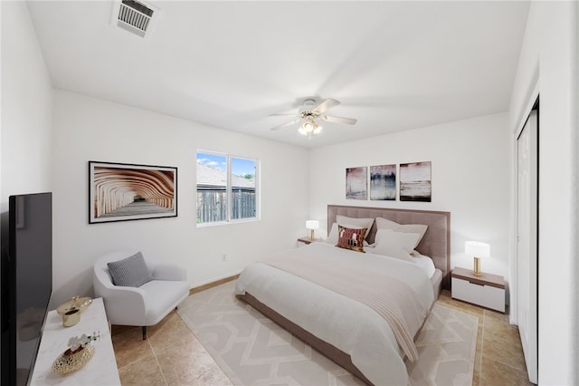 bedroom featuring a ceiling fan, baseboards, light tile patterned floors, visible vents, and a closet