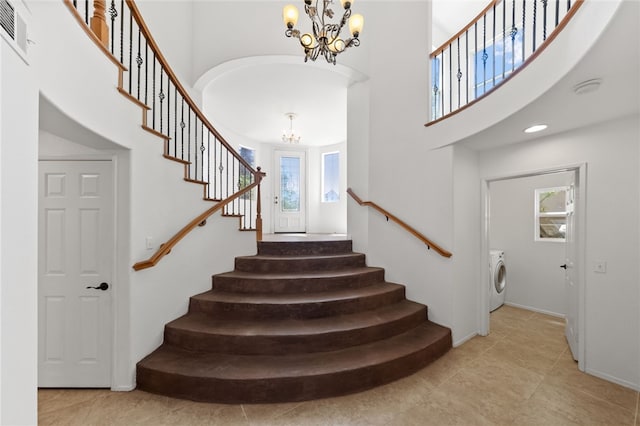 stairs featuring baseboards, washer / dryer, a high ceiling, and a chandelier