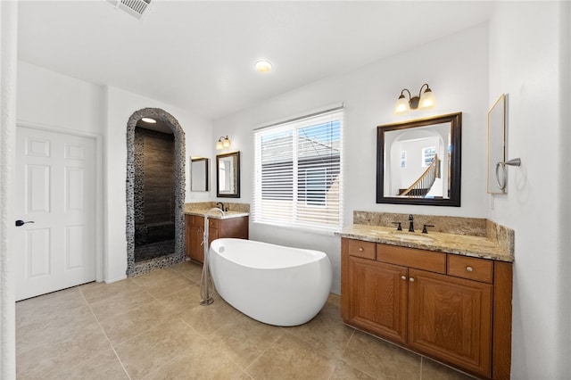 bathroom with visible vents, two vanities, a sink, and a freestanding bath