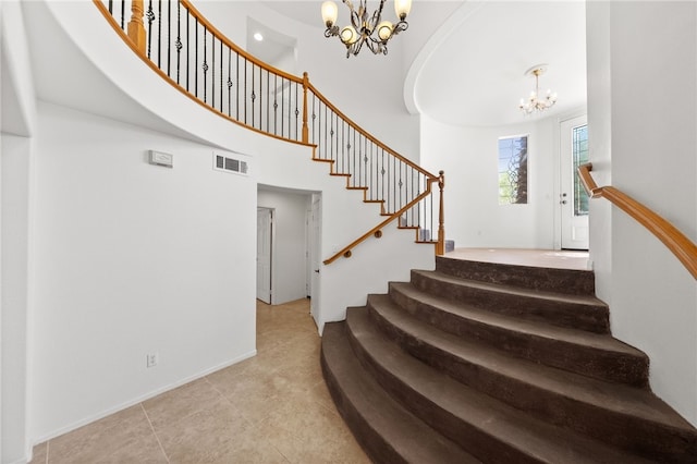 staircase featuring an inviting chandelier, baseboards, a towering ceiling, and visible vents