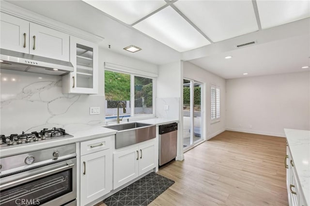 kitchen with white cabinetry, appliances with stainless steel finishes, under cabinet range hood, and a sink