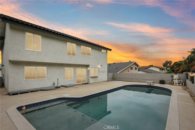 rear view of house with a fenced in pool, a fenced backyard, central air condition unit, a patio area, and stucco siding