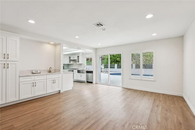interior space featuring white cabinets, light wood finished floors, light countertops, dishwasher, and visible vents