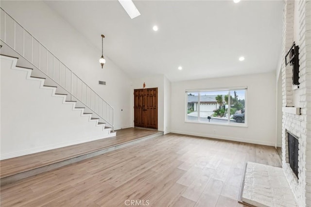 unfurnished living room with light wood-type flooring, baseboards, high vaulted ceiling, stairs, and a fireplace