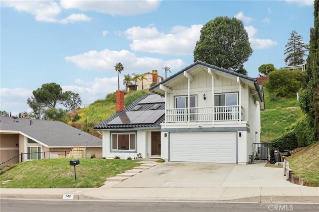 view of front of home with concrete driveway, roof mounted solar panels, fence, an attached garage, and a front yard