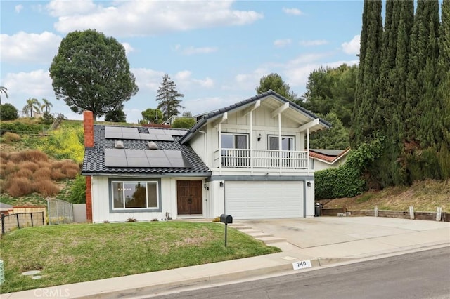 view of front of house with driveway, fence, a garage, roof mounted solar panels, and a front yard