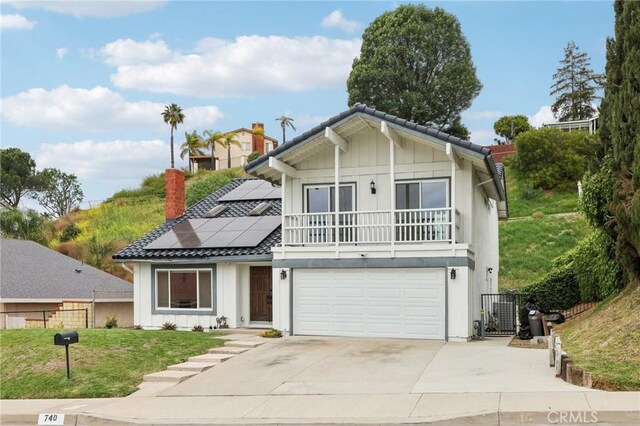 view of front of house with a front lawn, board and batten siding, an attached garage, fence, and solar panels