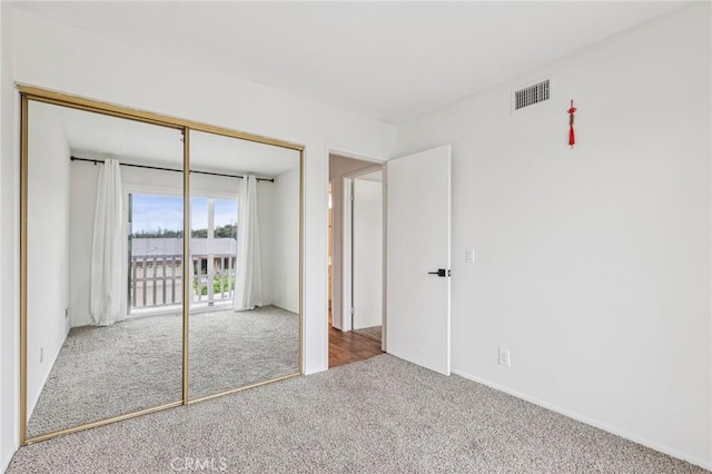 unfurnished bedroom with a closet, visible vents, carpet flooring, and access to outside