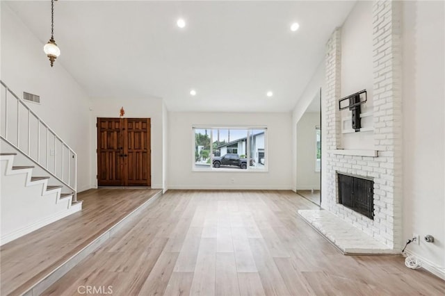 interior space with recessed lighting, visible vents, light wood-type flooring, a brick fireplace, and stairs
