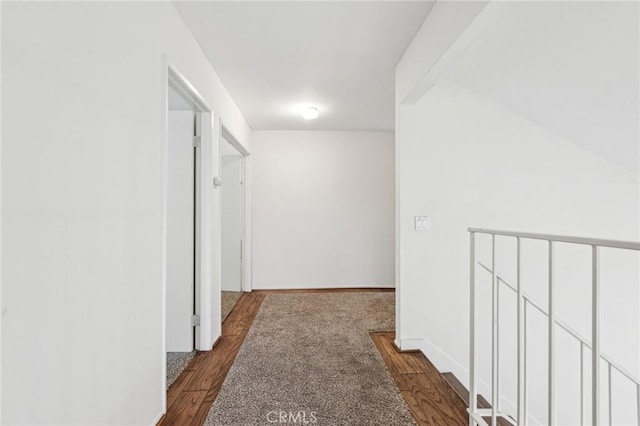 corridor featuring baseboards and dark wood finished floors
