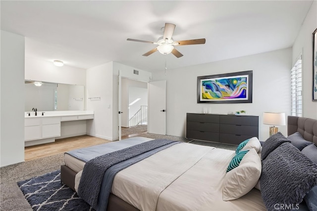 bedroom with light wood-type flooring, visible vents, a sink, and ceiling fan