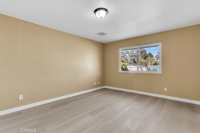 unfurnished room featuring wood finished floors, visible vents, and baseboards