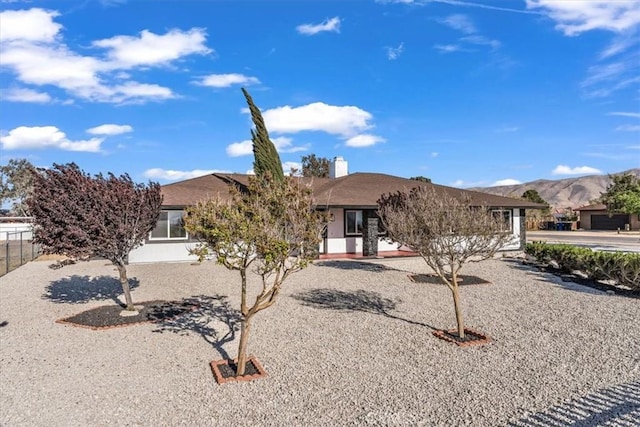 view of front of property with stucco siding, a chimney, fence, and a mountain view